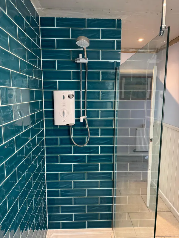 Walk-in shower with teal tiles and a glass screen