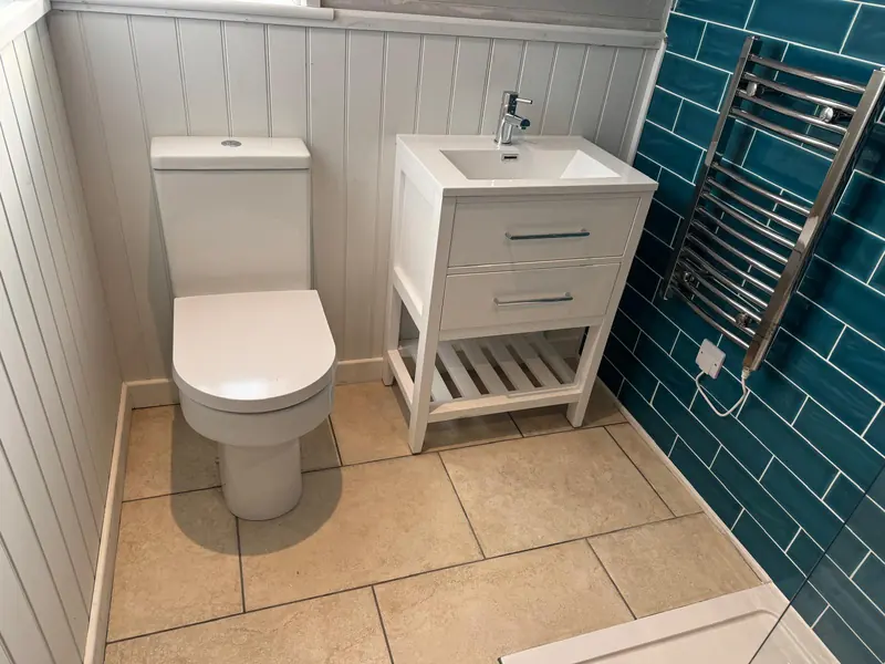 Bathroom with teal metro tiles, white panelling, vanity unit and towel rail